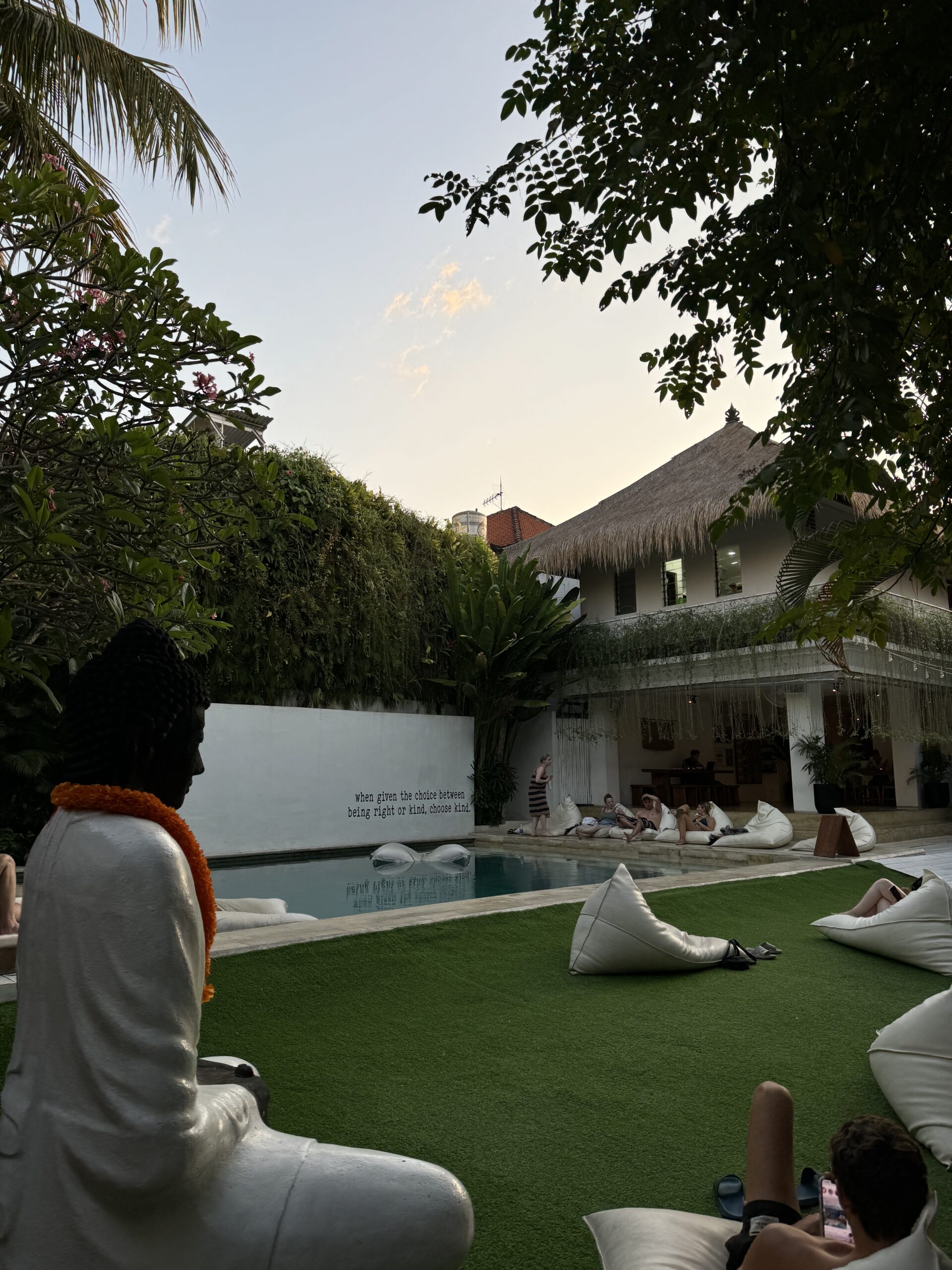 Buddha statue and bean bags in front of pool at sunset
