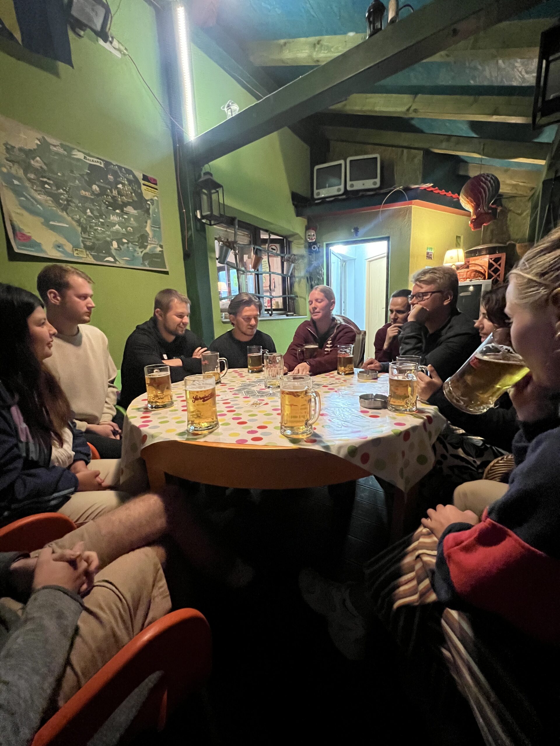 People sit in circle at table with beer and cards